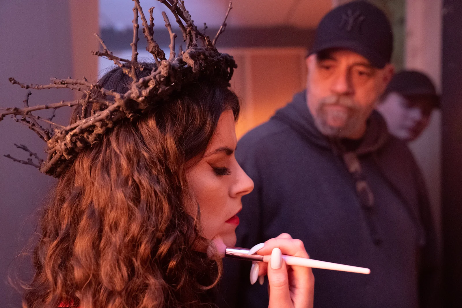 Makeup being applied to Cara beneath her twig crown