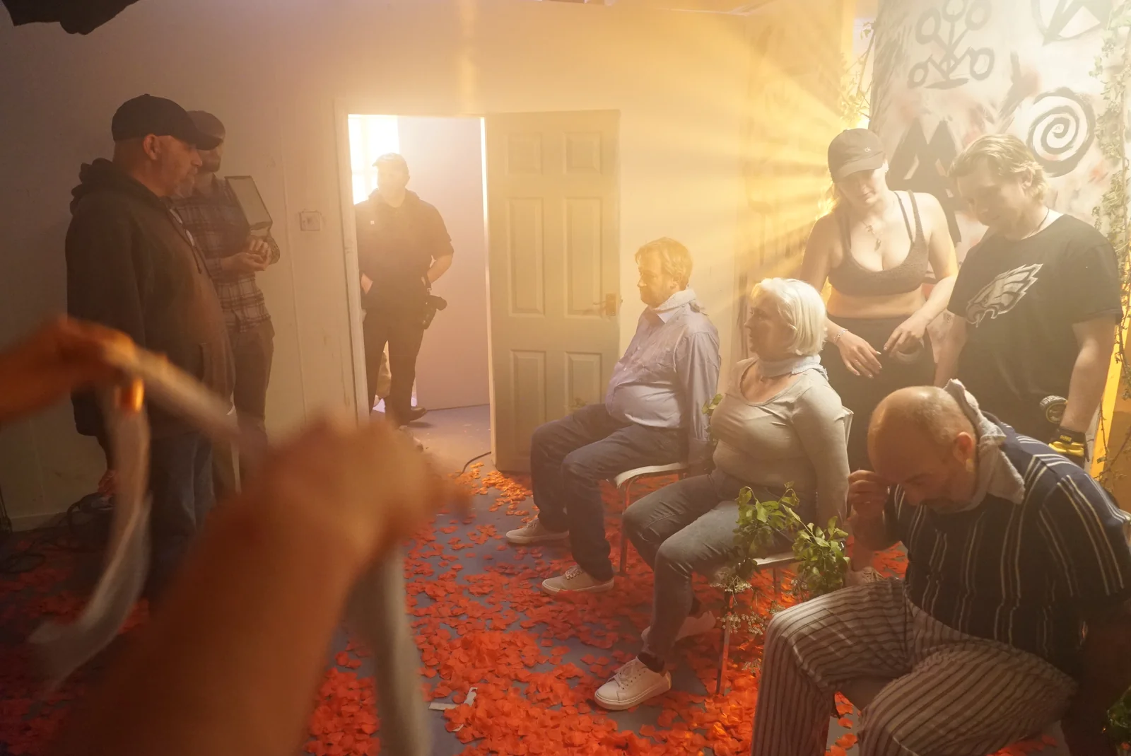 Cast and crew gathered in an amber-lit room filled with haze