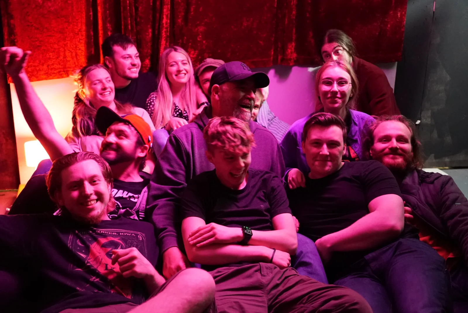 The crew posing together in pink and red set lighting